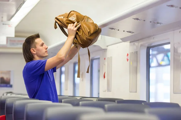 Junger Mann legt Gepäck in Schwebebahn bei Zug — Stockfoto
