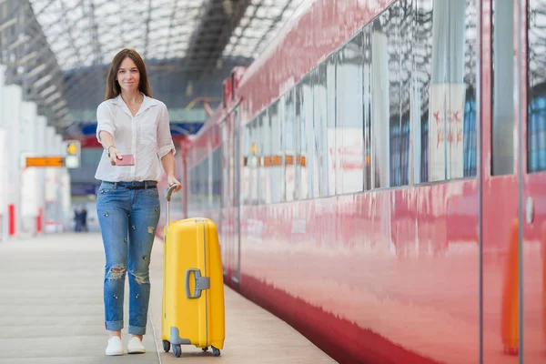 Ung kvinna med bagage vid en järnvägsstation. Kaukasiska turist väntar hennes expresståg medan hennes resor. — Stockfoto