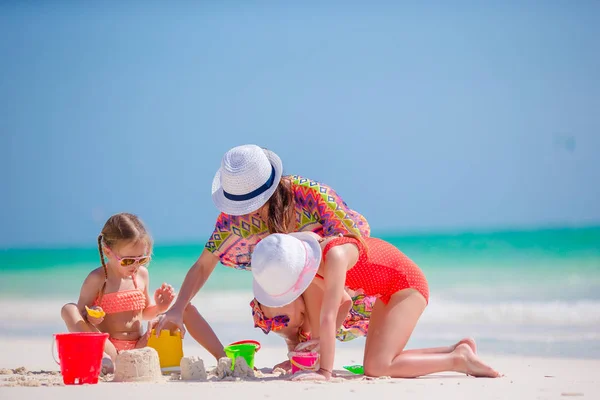 Anne ve iki çocuğu tropik sahilde kum ile oynuyor. Aile kurmak bir new castle. — Stok fotoğraf