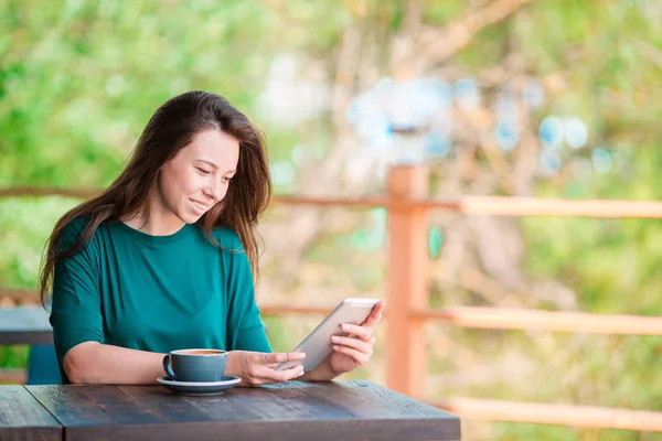 Jeune femme avec téléphone intelligent assis seul dans un café pendant le temps libre — Photo