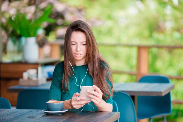 空余时间一个人坐在咖啡店里，拿着智能手机的年轻女人 — 图库照片