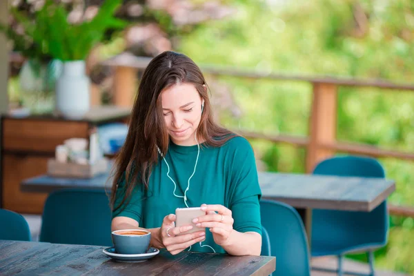 Молодая женщина со смартфоном, сидя одна в кафе в свободное время — стоковое фото