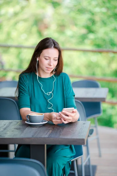 Молодая женщина со смартфоном, сидя одна в кафе в свободное время — стоковое фото