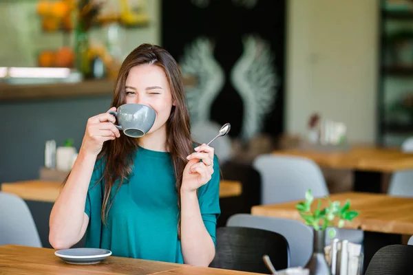 Piękna elegancka dziewczyna jedząca śniadanie w kawiarni na świeżym powietrzu. Szczęśliwa młoda miejska kobieta pijąca kawę — Zdjęcie stockowe