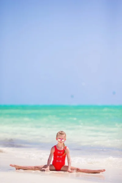 Aktives kleines Mädchen am weißen Strand, das Spaß hat — Stockfoto