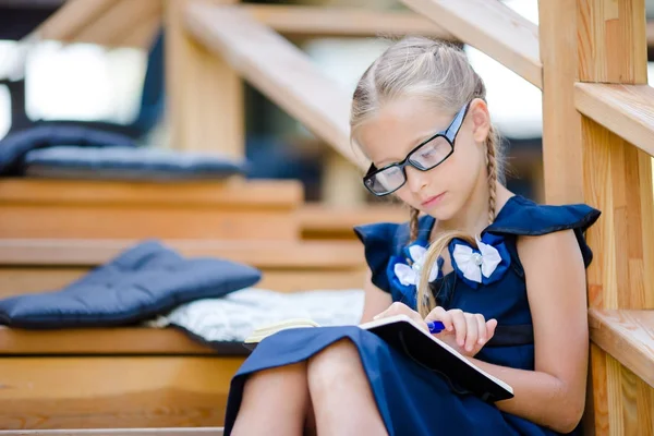 Schattige kleine school meisje met notities en potloden buiten. Terug naar school. — Stockfoto