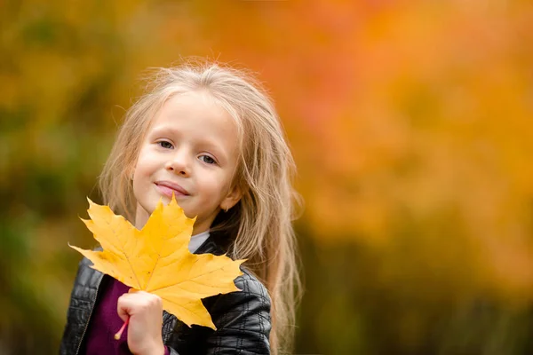 Portrait d'adorable petite fille avec bouquet de feuilles jaunes en automne sur scooter — Photo