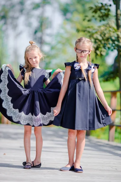 Schattige kleine schoolmeisjes buitenshuis in warme dag van september. Terug naar school. — Stockfoto