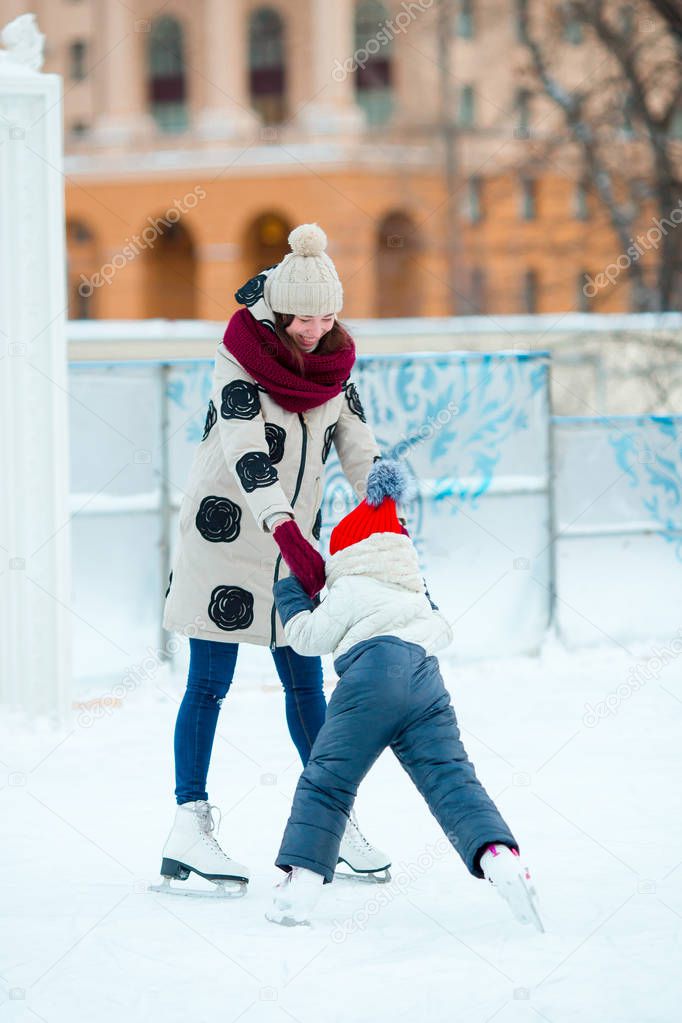 Little adorable girl with mother skating on ice-rink with mother