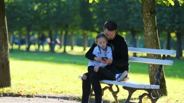 Sonbaharda mutlu bir aile. Smartphone ve sonbaharda açık havada küçük çocuk ile baba — Stok video