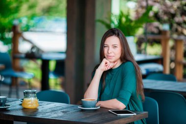Güzel bir kadın açık kafede kahvaltı yapıyor. Mutlu genç şehir kadını kahve içiyor.