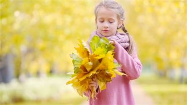 Güzel bir sonbahar gününde, sarı ve turuncu yapraklı sevimli küçük bir kızın portresi.
