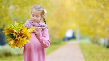 Güzel bir sonbahar gününde, sarı ve turuncu yapraklı sevimli küçük bir kızın portresi.