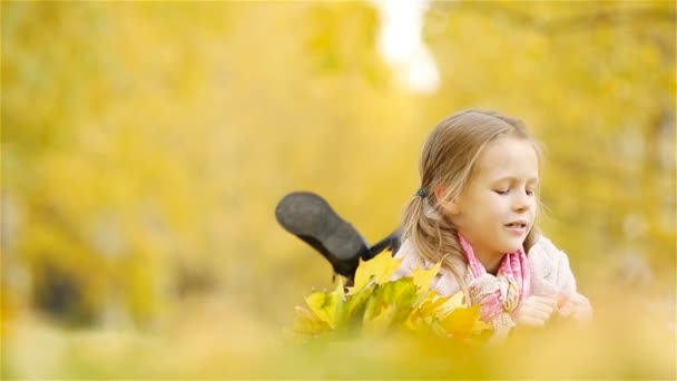 Ritratto di adorabile bambina con bouquet di foglie gialle in autunno. Bellissimo bambino sorridente sdraiato sul tappeto foglie — Video Stock