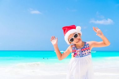 Noel Baba şapkası Noel beach tatil sırasında sevimli küçük kız. Küçük çocuğa Noel plaj tatil