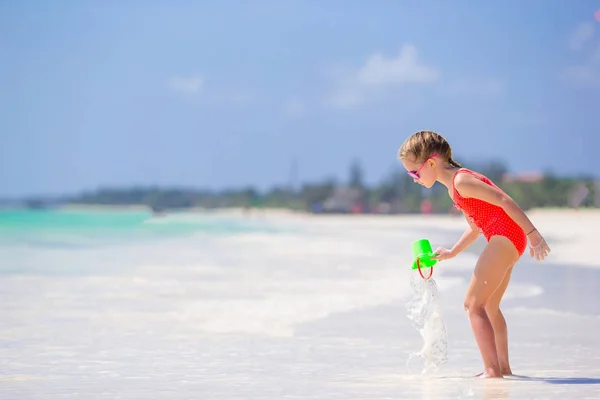 Malá dívka na tropické bílé pláži tvorby písku hrad — Stock fotografie
