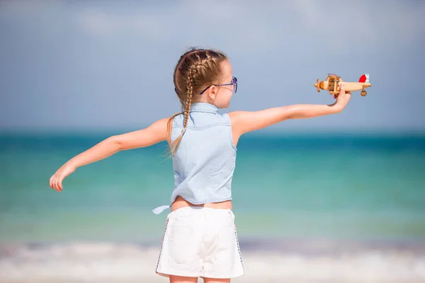 Gelukkig klein kind met speelgoed vliegtuig in handen op witte zandstrand — Stockfoto