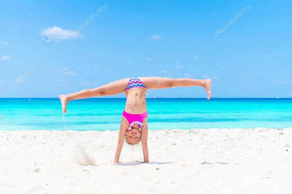 Active little girl at beach having a lot of fun on summer vacation. Adorable kid jumping on the seashore