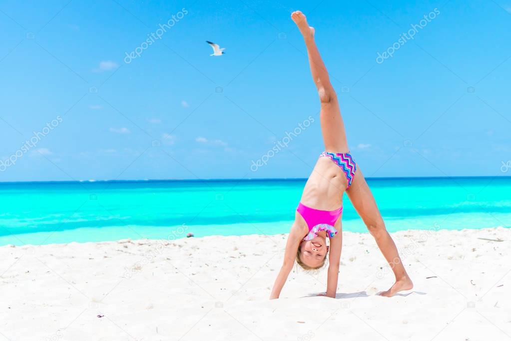 Amazing little girl at beach having a lot of fun on summer vacation. Adorable kid jumping on the seashore
