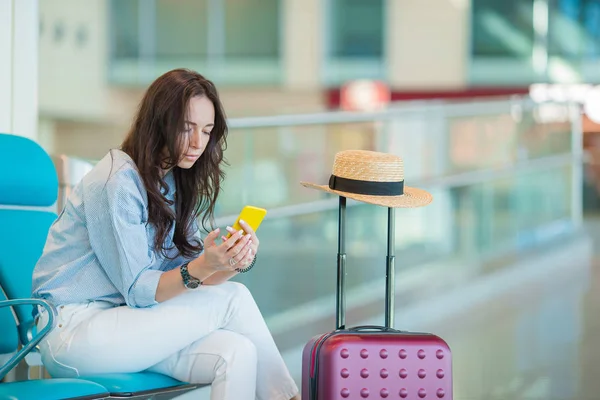 Молодая женщина со смартфоном в международном аэропорту ждет полета самолета — стоковое фото