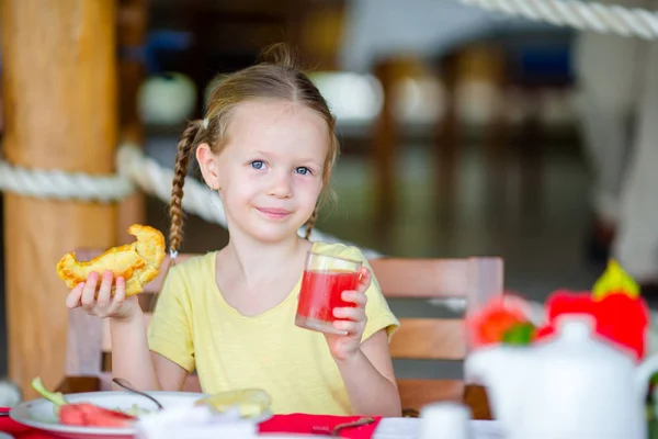 Adorable niña tomando el desayuno en la cafetería al aire libre —  Fotos de Stock