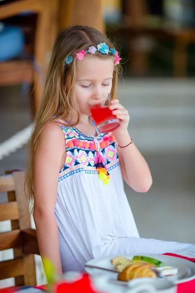 Adorable niña tomando el desayuno en la cafetería al aire libre. Tapa bebiendo jugo fresco — Foto de Stock