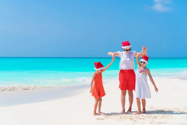 Szczęśliwa rodzina piękna mama i dzieci w czerwone kapelusze Santa na tropikalnej plaży na święta — Zdjęcie stockowe