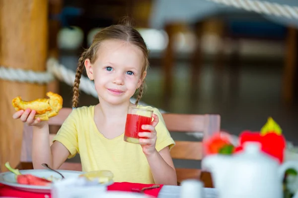 Adorable niña tomando el desayuno en la cafetería al aire libre —  Fotos de Stock