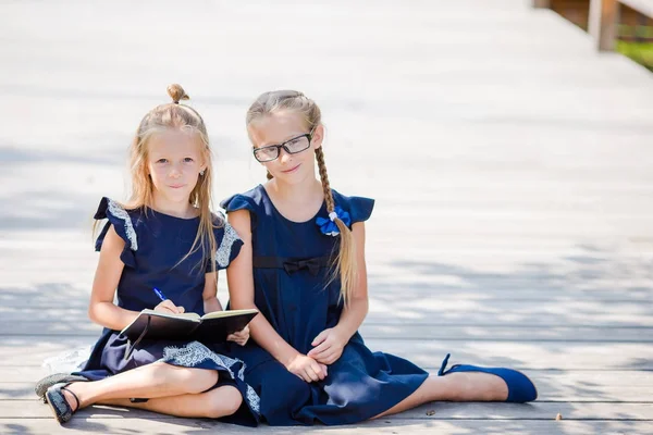 Meninas adoráveis da escola com notas e lápis ao ar livre. De volta à escola . — Fotografia de Stock