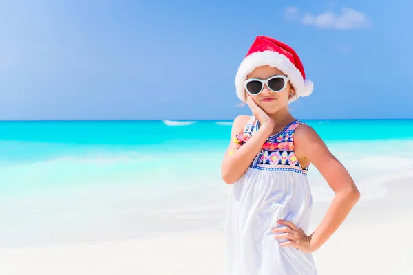 Αξιολάτρευτο κοριτσάκι στο Santa καπέλο κατά τη διάρκεια διακοπών παραλία Χριστουγέννων — Φωτογραφία Αρχείου