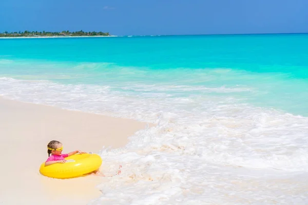 Felice bambina con cerchio di gomma gonfiabile che si diverte sulla spiaggia in acqua poco profonda — Foto Stock