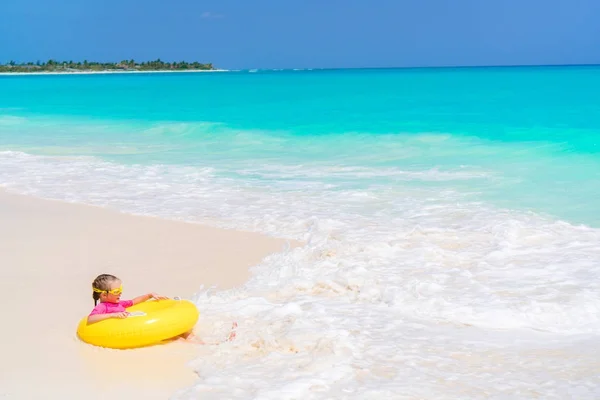 Happy little girl with inflatable rubber circle having fun on the beach in yhe shallow water — Stock Photo, Image