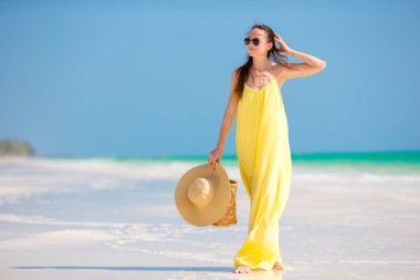 Tropikal plaj tatil sırasında şapka ile sarı elbiseli genç kadın