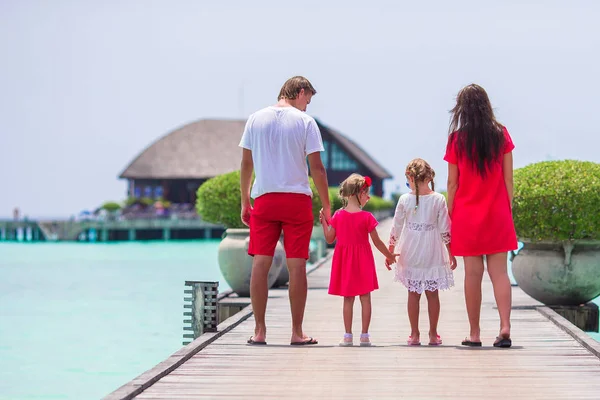 Familia joven en rojo sobre embarcadero de madera en Maldivas — Foto de Stock