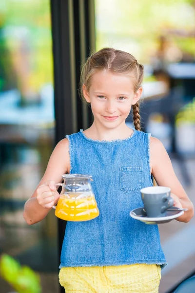 Adorable little girl having breakfast at cafe early in the morning — Stock Photo, Image