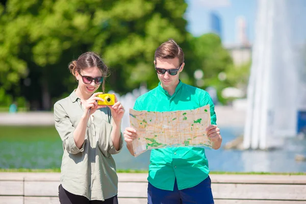 Pareja joven viajando de vacaciones en Europa sonriendo feliz. Familia caucásica con mapa de la ciudad en busca de atracciones — Foto de Stock