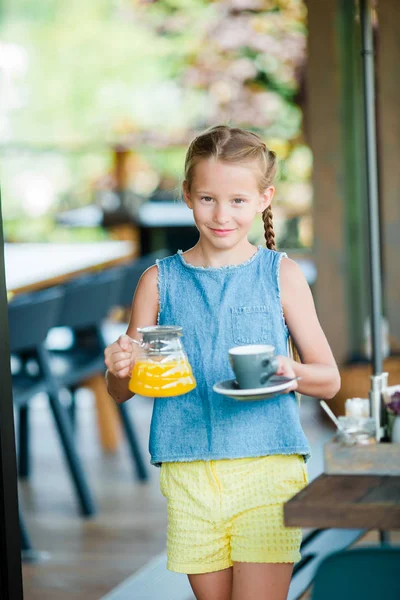 Adorable niña tomando el desayuno en la cafetería temprano en la mañana —  Fotos de Stock