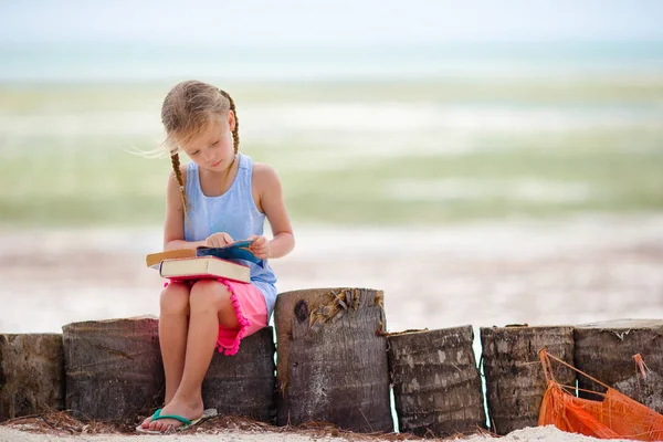 Little adorable girl with book on tropical white beach — Stock Photo, Image