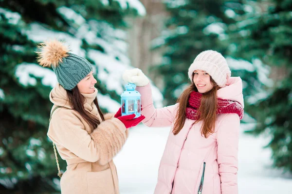 Young girls holding Christmas candlelight outdoors on beautiful winter snow day and warm their hands — Stock Photo, Image