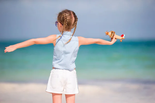Šťastné dítě dívka si hraje s hračkou letadla na pláži. Kid sen stát se pilotem — Stock fotografie
