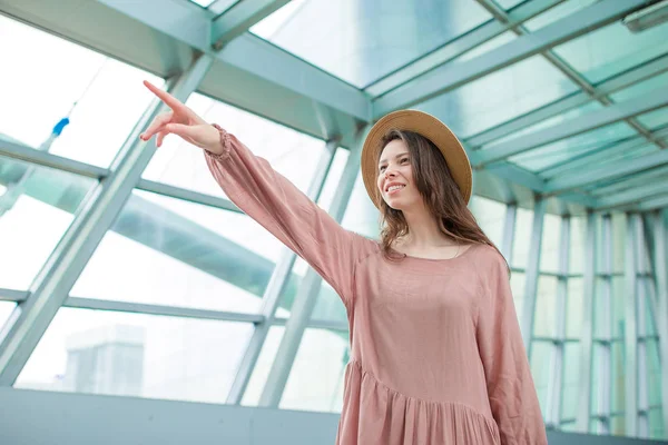 美しい女性を空港ラウンジで搭乗を待っています。国際空港で帽子でハッピー ガール — ストック写真