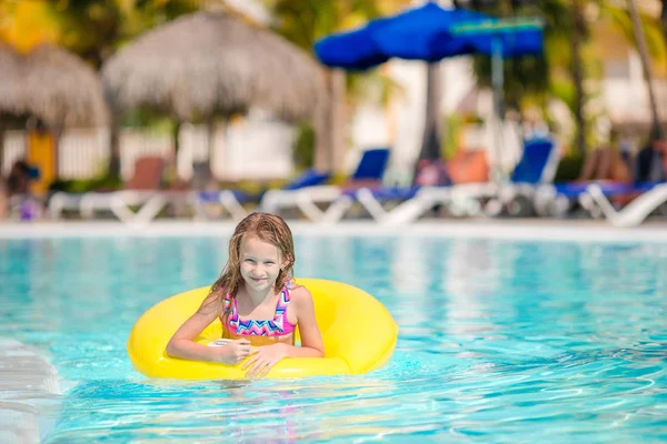 Маленькая девочка с надувным резиновым кругом, развлекающаяся в открытом бассейне в роскошном отеле — стоковое фото