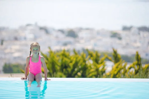 Αξιολάτρευτο κοριτσάκι, στην άκρη από την εξωτερική πισίνα με όμορφη θέα — Φωτογραφία Αρχείου
