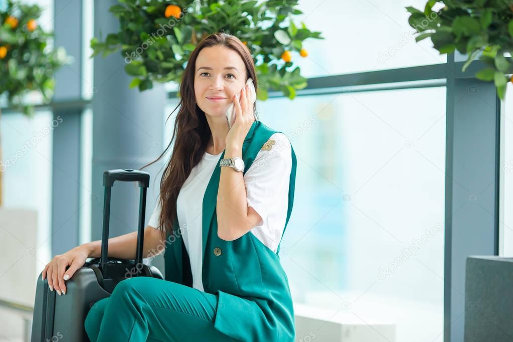 Portrait of young woman with smartphone in international airport. Airline passenger in an airport lounge waiting for flight aircraft