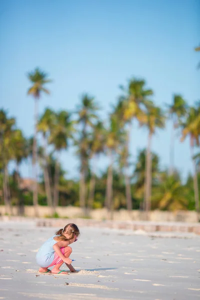 Adorable little girl drawing on white sand at the beach — Stock Photo, Image