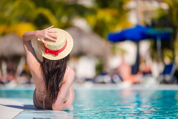 Mulher jovem bonita relaxante na borda da piscina infiniti — Fotografia de Stock