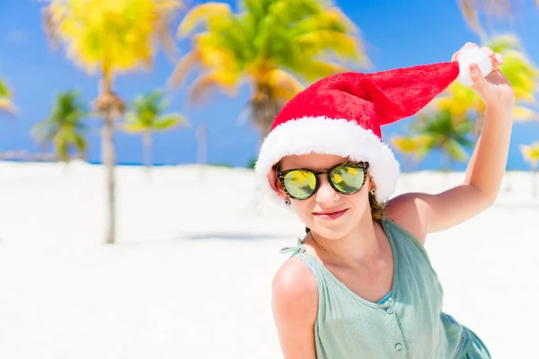 Fröhliche lustige kleine Mädchen mit Weihnachtsmütze während der Weihnachtsferien am Strand haben eine Menge Spaß — Stockfoto