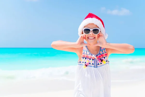 Felice bambina a Babbo Natale cappello durante le vacanze al mare di Natale hanno un sacco di divertimento — Foto Stock
