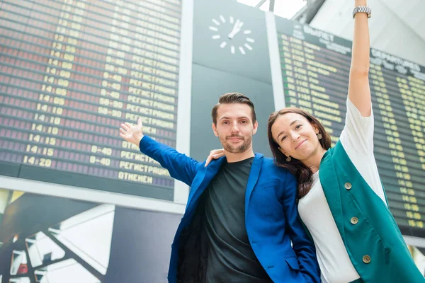 Família de dois no fundo do aeroporto internacional a bordo de informações de voo — Fotografia de Stock