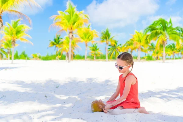 Kleines entzückendes Mädchen mit großer Kokosnuss am weißen Sandstrand — Stockfoto